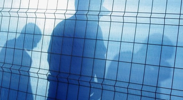 L'ombre d'un officier de police espagnol (C) et de deux des 124 immigrants clandestins interceptés en mer par un navire des garde-côtes espagnols dans le port de Los Cristianos, sur l'île espagnole de Tenerife, aux Canaries, le 8 septembre 2006.