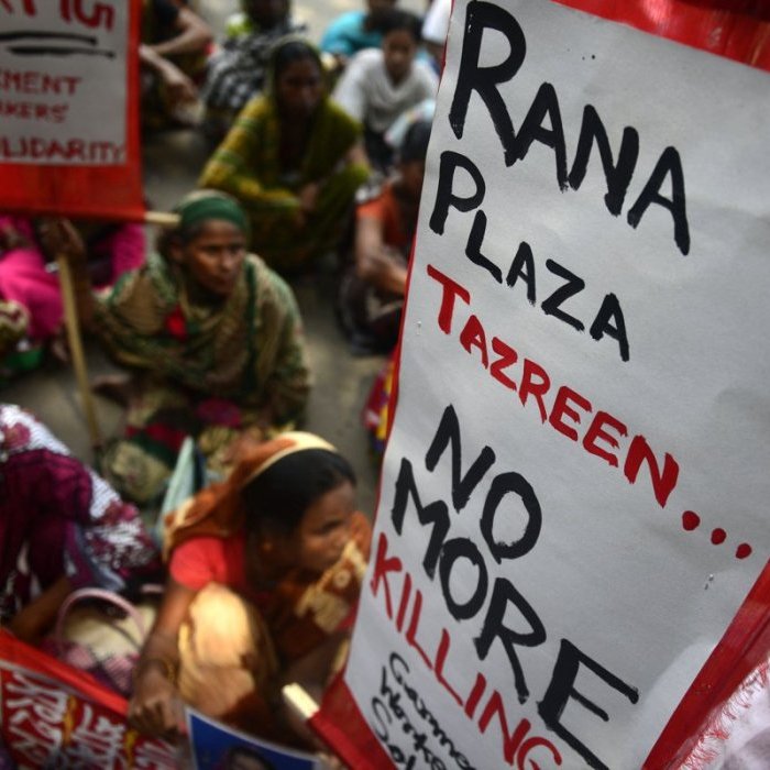 Au Bangladesh, des travailleurs/euses de l'habillement tiennent des pancartes lors d'une manifestation sur les salaires et les compensations à Dhaka, le 13 septembre 2013. Des centaines de travailleurs ont pris part à la manifestation pour réclamer un salaire mensuel minimum de 103 USD et une indemnisation pour les victimes et les blessés de l'effondrement de l'immeuble Rana Plaza du 24 avril.