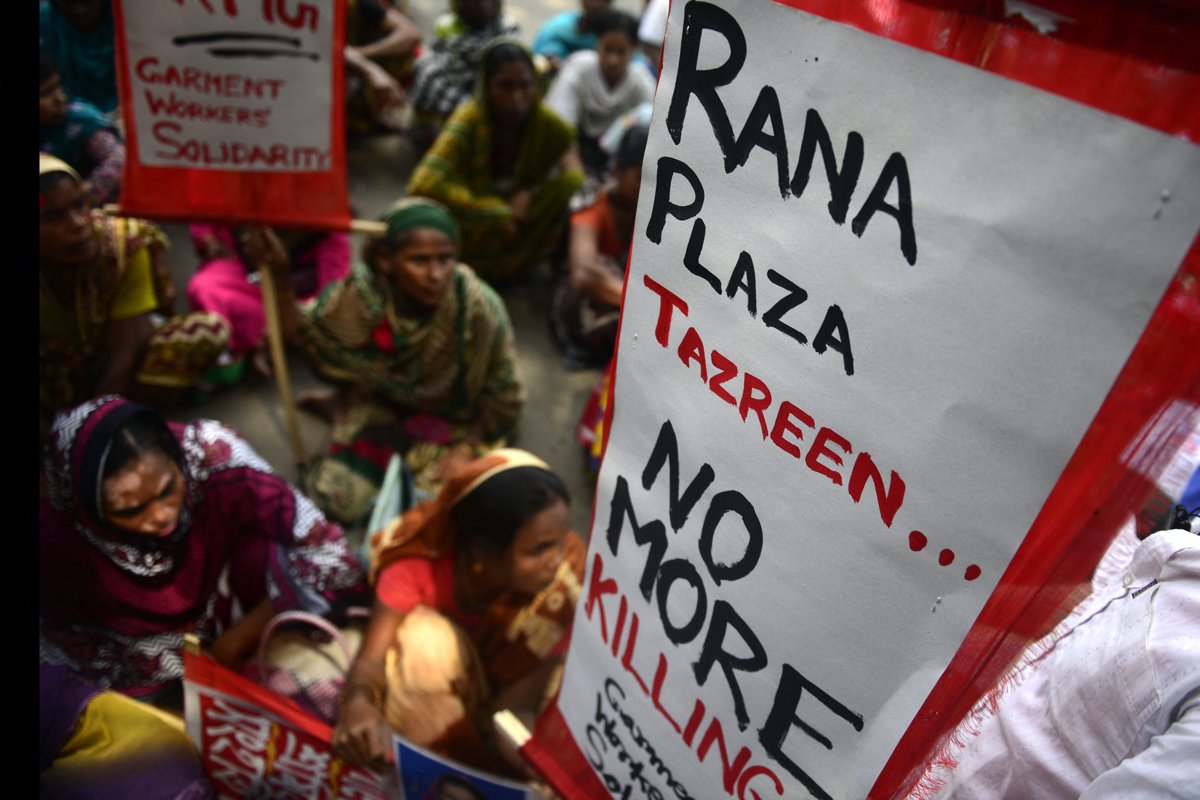 Au Bangladesh, des travailleurs/euses de l'habillement tiennent des pancartes lors d'une manifestation sur les salaires et les compensations à Dhaka, le 13 septembre 2013. Des centaines de travailleurs ont pris part à la manifestation pour réclamer un salaire mensuel minimum de 103 USD et une indemnisation pour les victimes et les blessés de l'effondrement de l'immeuble Rana Plaza du 24 avril.