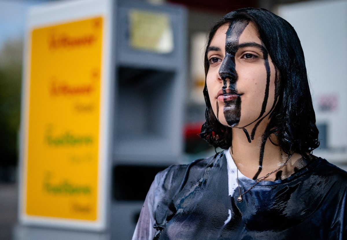 Une manifestante couverte de peinture noire participe à une action appelée par le mouvement Extinction Rebellion et le groupe néerlandais de militants pour le climat Code Rood, dans une station-service Shell à La Haye, le 18 mai 2021, pour protester contre la politique du groupe Shell, qui selon les militants, choisit le profit au détriment du climat, de la nature et des vies humaines.