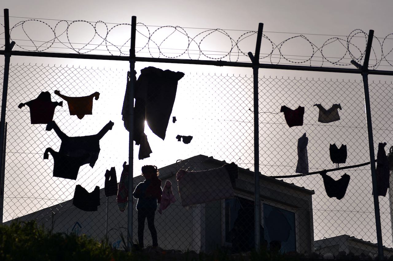 Des enfants font sécher leur linge derrière une clôture du centre de détention VIAL sur l'île de Chios où sont gardés les personnes migrantes arrivées après l'accord UE-Turquie. 