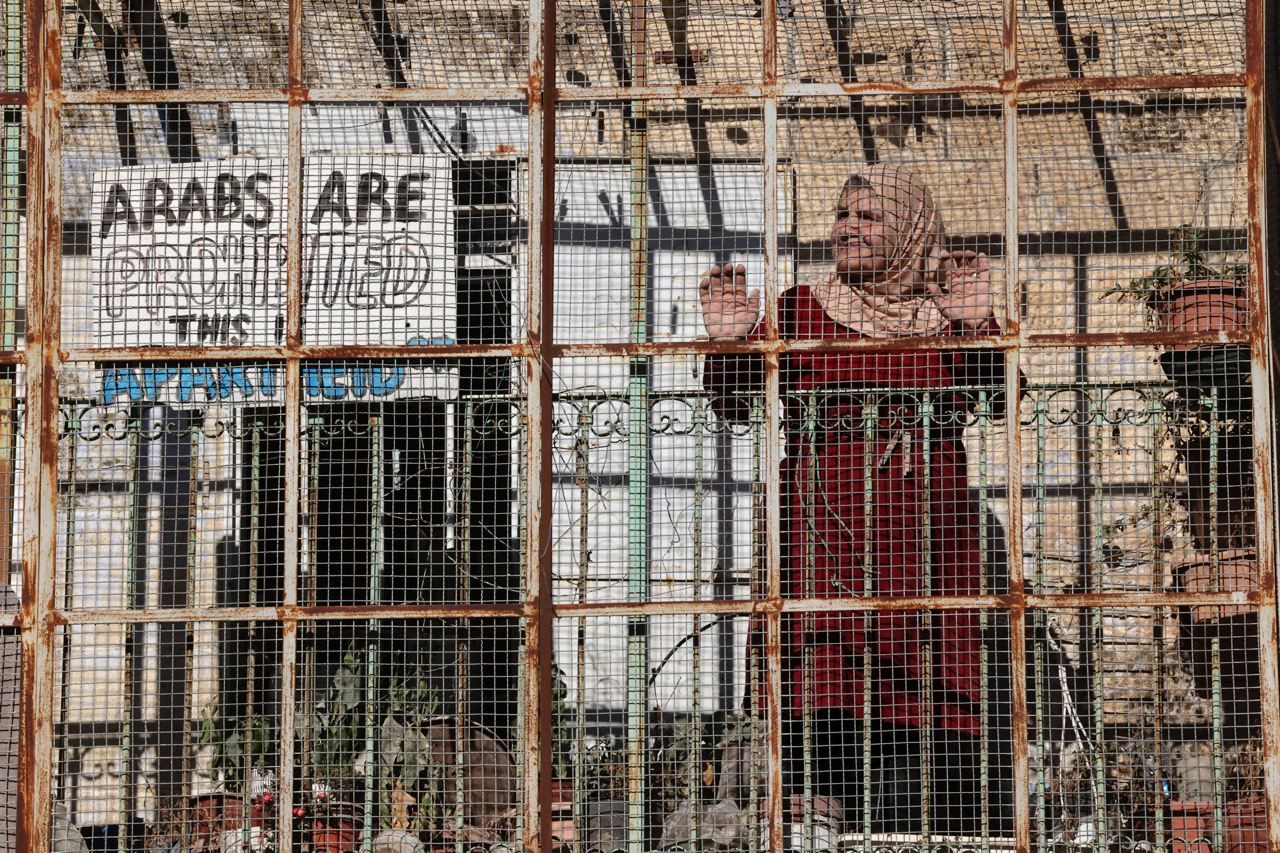 Novembre 2021. Une femme palestinienne se tient devant la clôture de sa maison dans la rue al-shuhada, qui est en grande partie fermée aux Palestiniens, dans la ville palestinienne d'Hébron. 